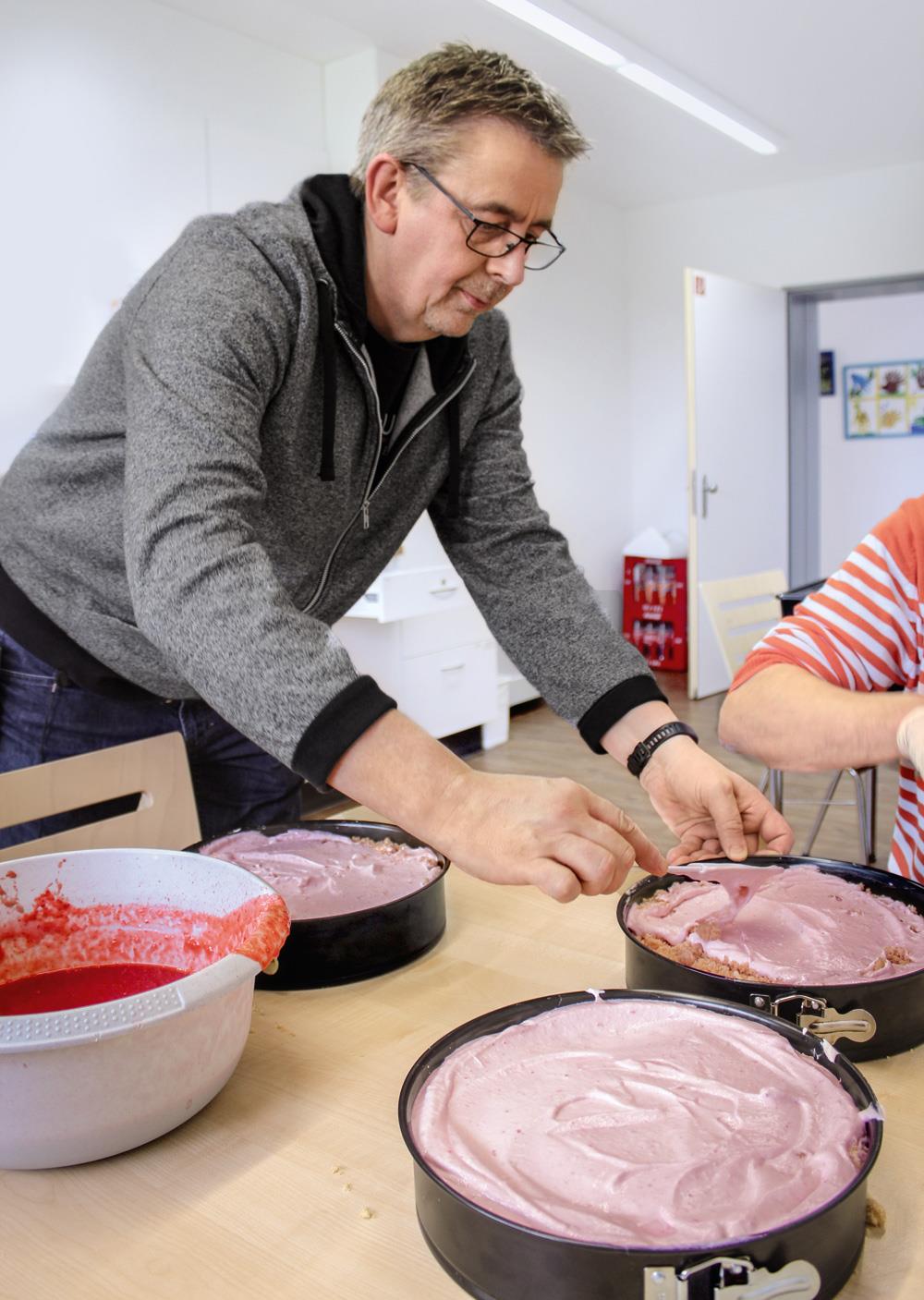 Mann bestreicht einen Kuchen mit Messer