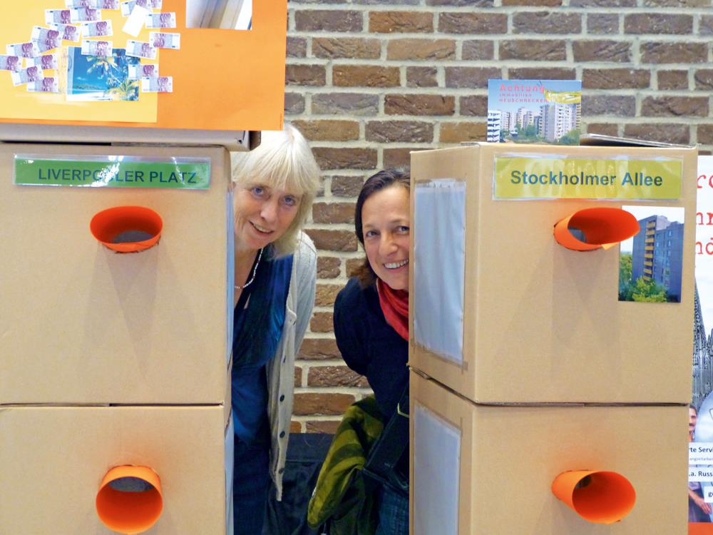 Zwei Frauen blicken hinter Kartons hervor.