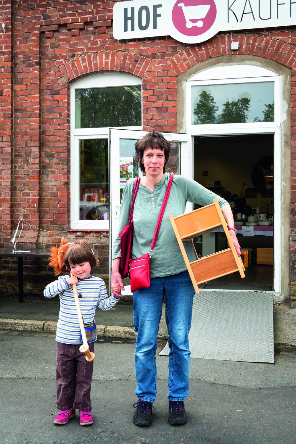 Eine Mutter mit ihrem Kind haben in den Goslarschen Höfen ein Kleinmöbel und ein Steckenpferd gekauft.