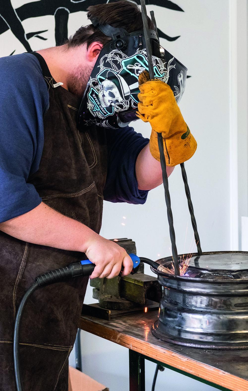 An eine alte Autofelge werden Stahlbeine geschweißt.
