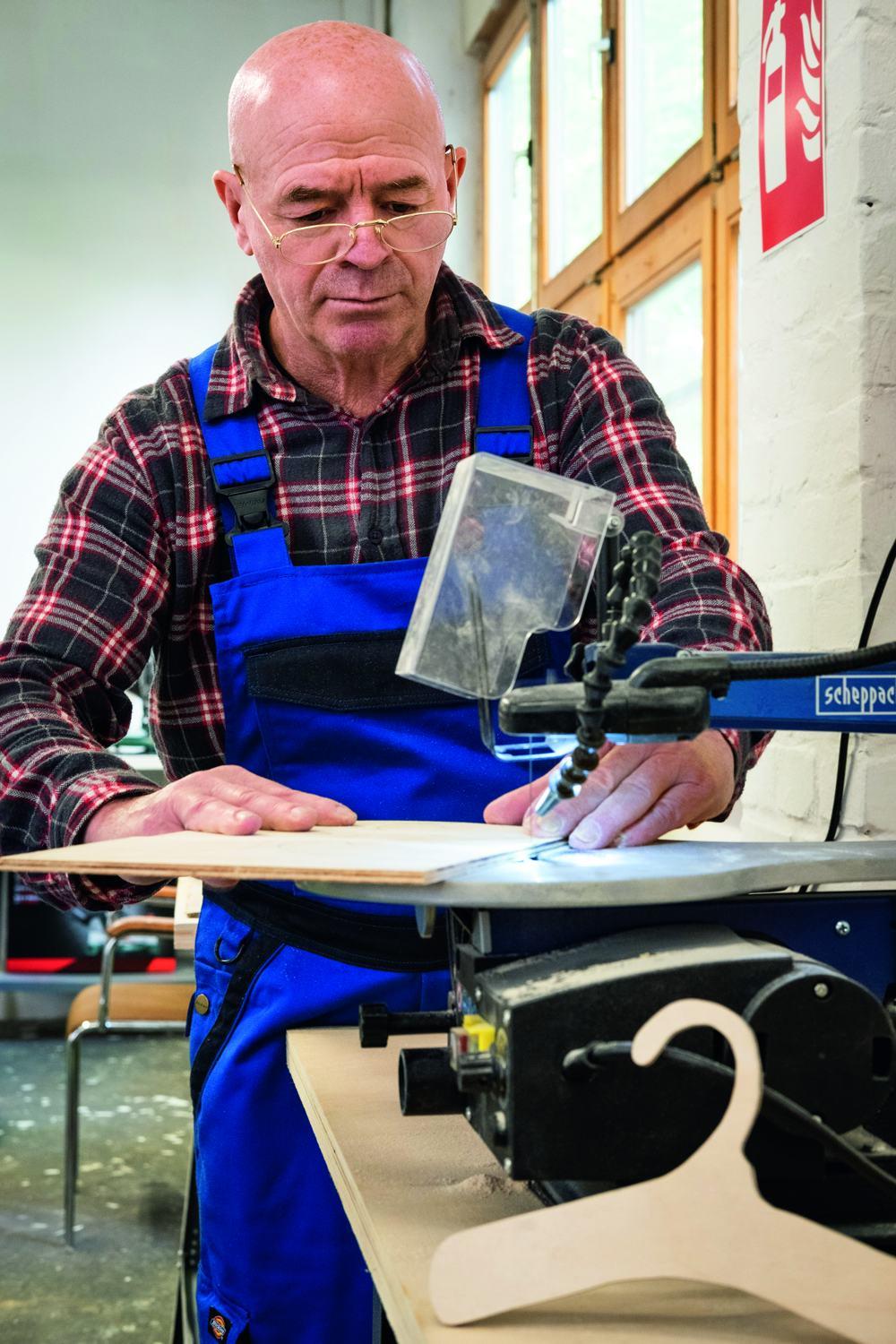 Ein Mitarbeiter der Goslarschen Höfe arbeitet konzentriert an einer Stichsäge-Standmaschine.