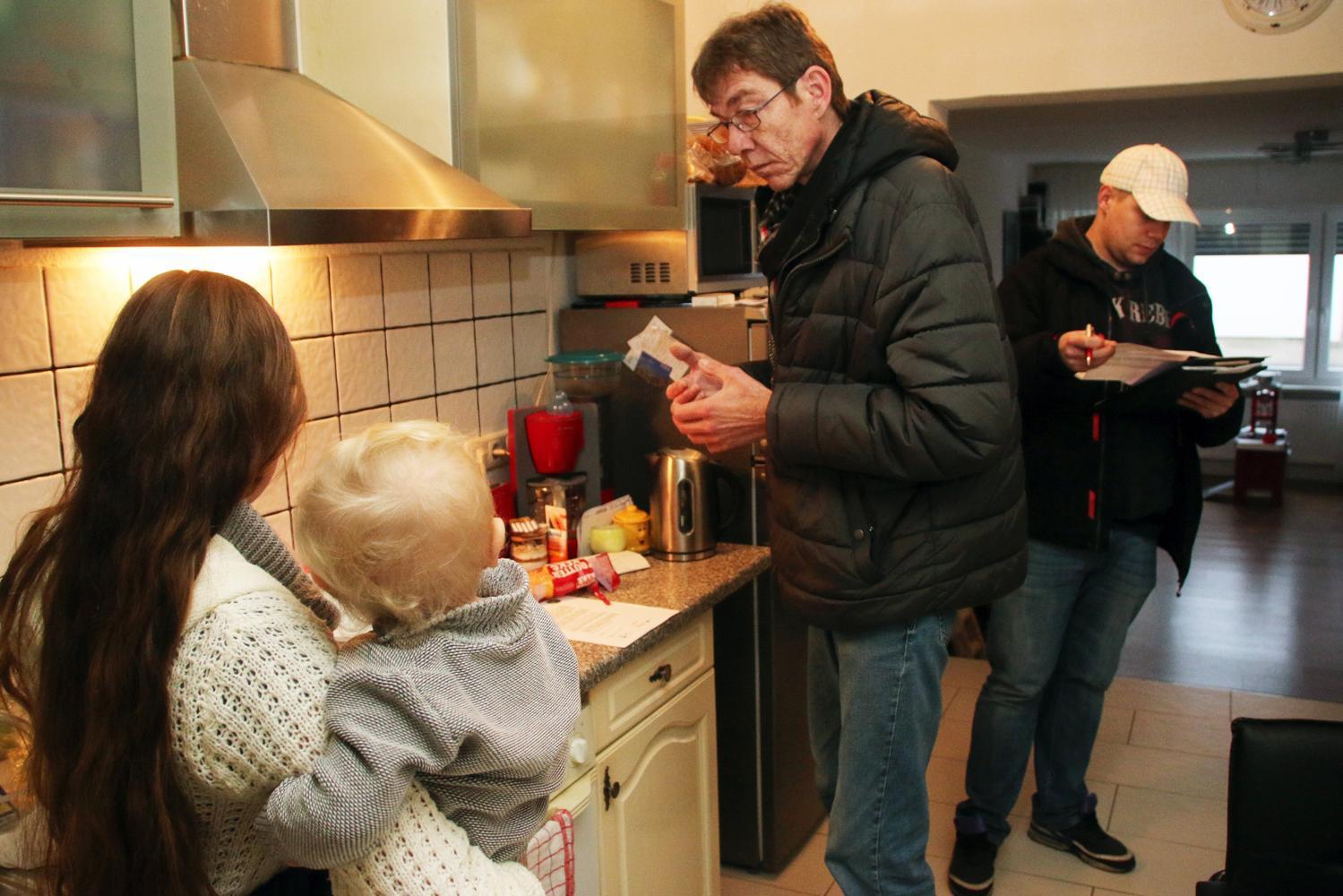 Zwei Stromspar-Checker prüfen die Elektro-Geräte in der Wohnung einer jungen Mutter.