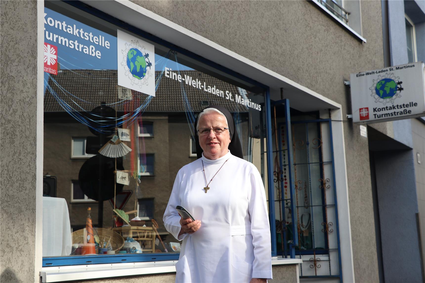 Auf dem Bild steht eine Schwester vor dem Eine-Welt-Laden