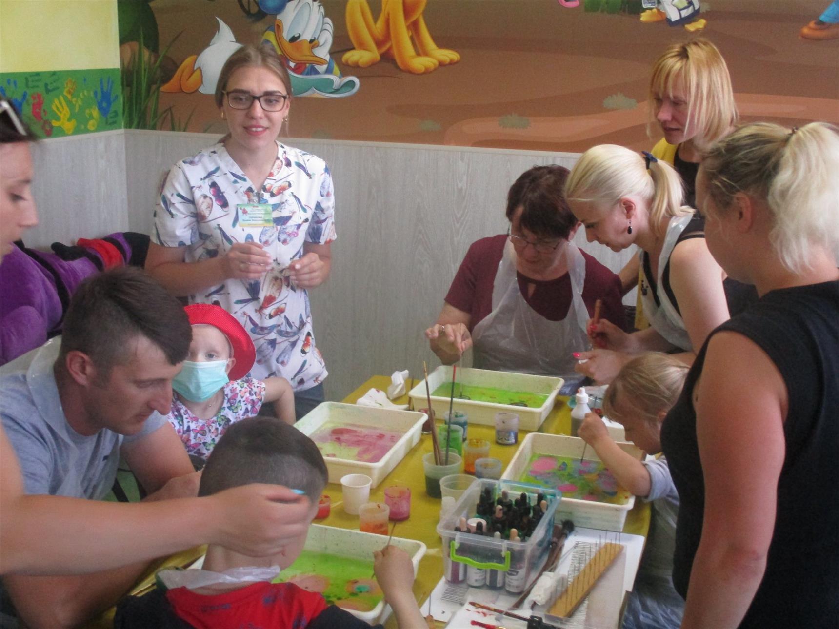 Mitarbeiter der Klinik und Eltern der kleinen Patienten gestalten mit den Kindern in der Maltherapie Bilder.