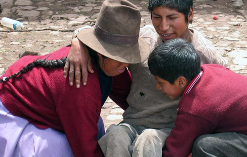 Eine Frau mit Hut und ein kleiner Junge heben einen älteren Jungen hoch