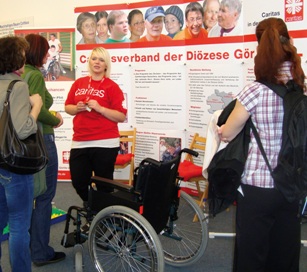 Eine Mitarbeiterin der Caritas im Gespräch mit Besuchern der Impuls-Messe 