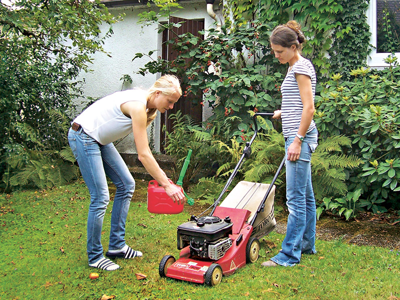 Zwei junge Frauen mit Rasenmäher bei der Gartenarbeit