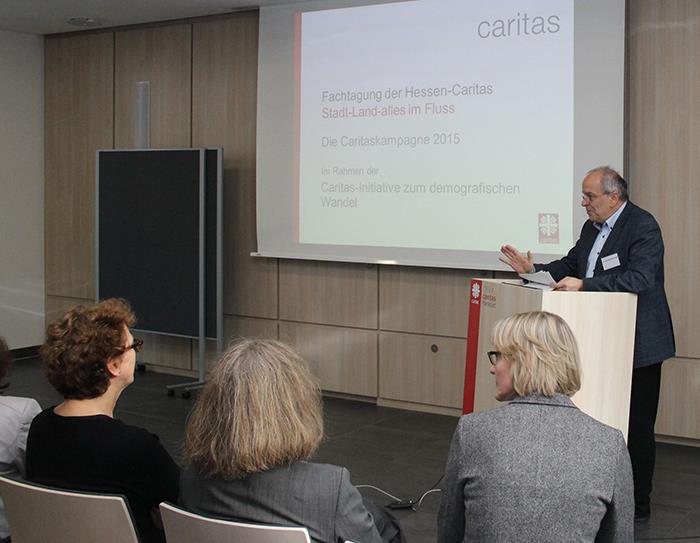 Ein Redner steht hinter dem Pult und spricht in ein Mikrofon. 