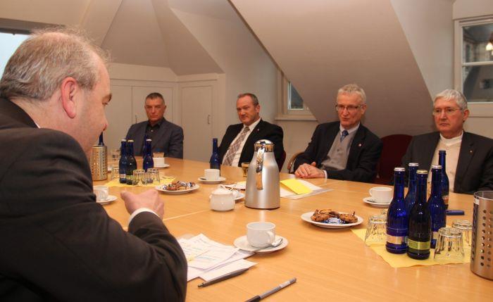 Die Verantwortlichen von Staat und Caritas sitzen am großen Tisch in der Geschäftsstelle des Verbandes.