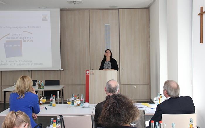 Eine Frau steht hinter einem Rednerpult und spricht zu den Teilnehmern.