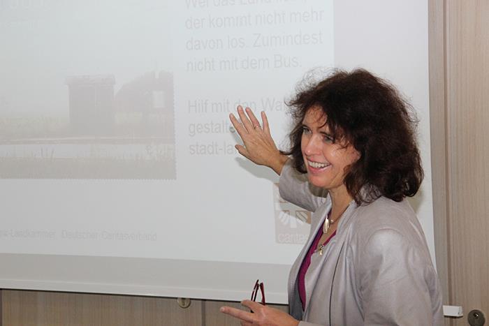 Die Referentin steht rechts im Bild und weißt mit ihrer rechten Hand auf die Leinwand.