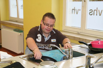 Ein junger Mensch sitzt vor einem grpßen Spülbecken.