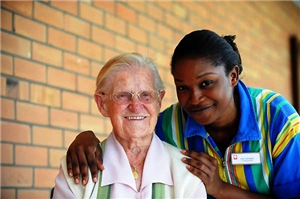 Alte Damen mit dunkelhäutiger Pflegerin